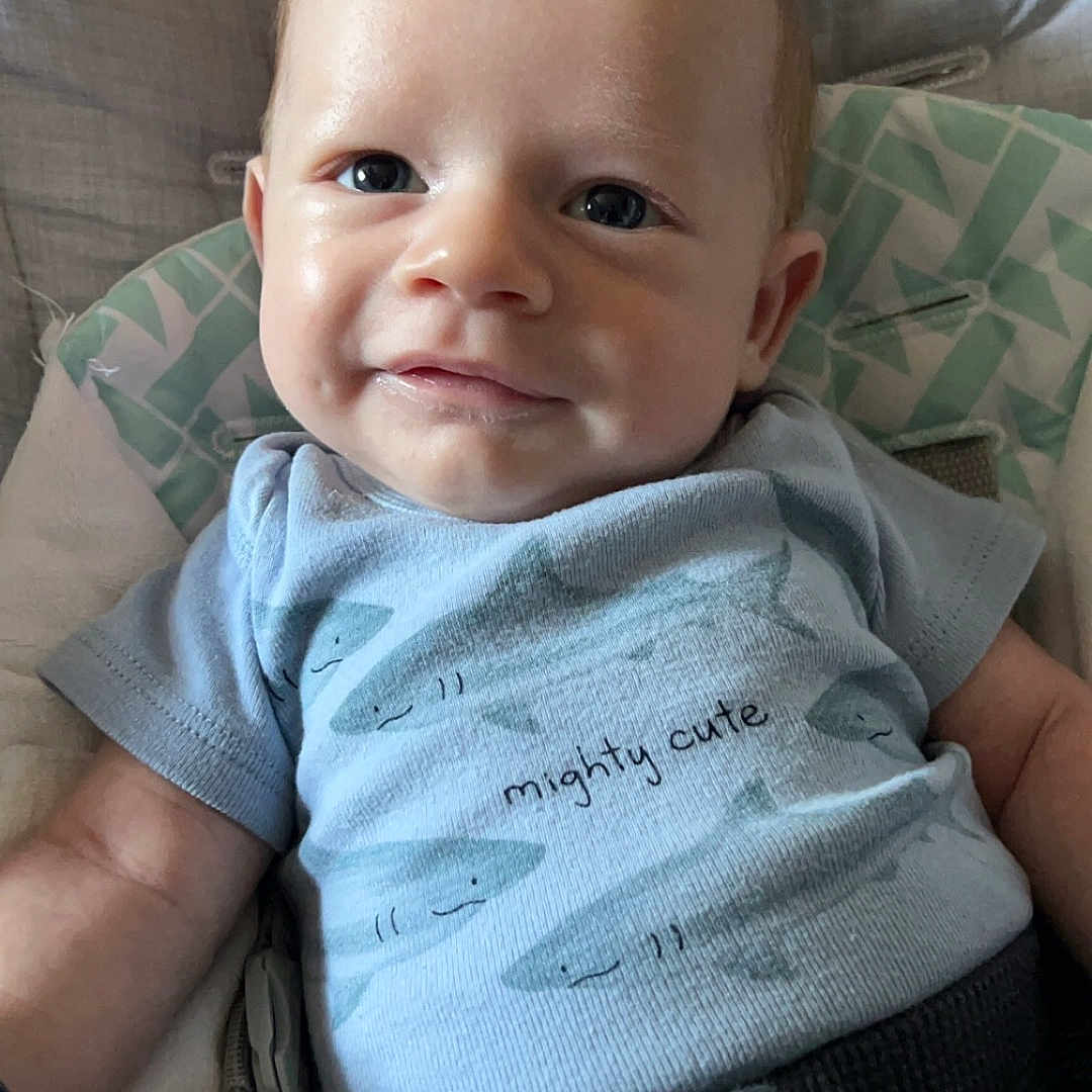 Jacob is registered to the contest to win money with this photo: baby, bed, blanket, clothing, couch, cushion, face, furniture, happy, head, homedecor, linen, newborn, pants, person, photography, portrait, sitting, smile, t_shirt