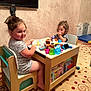 Brando is registered to the contest to win money with this photo: child, toddler, toy, table, book, chair, indoor, carpet, television, furniture, play, curly_hair, short_sleeves, wooden_furniture, colorful, smile, person, room, learning, fun