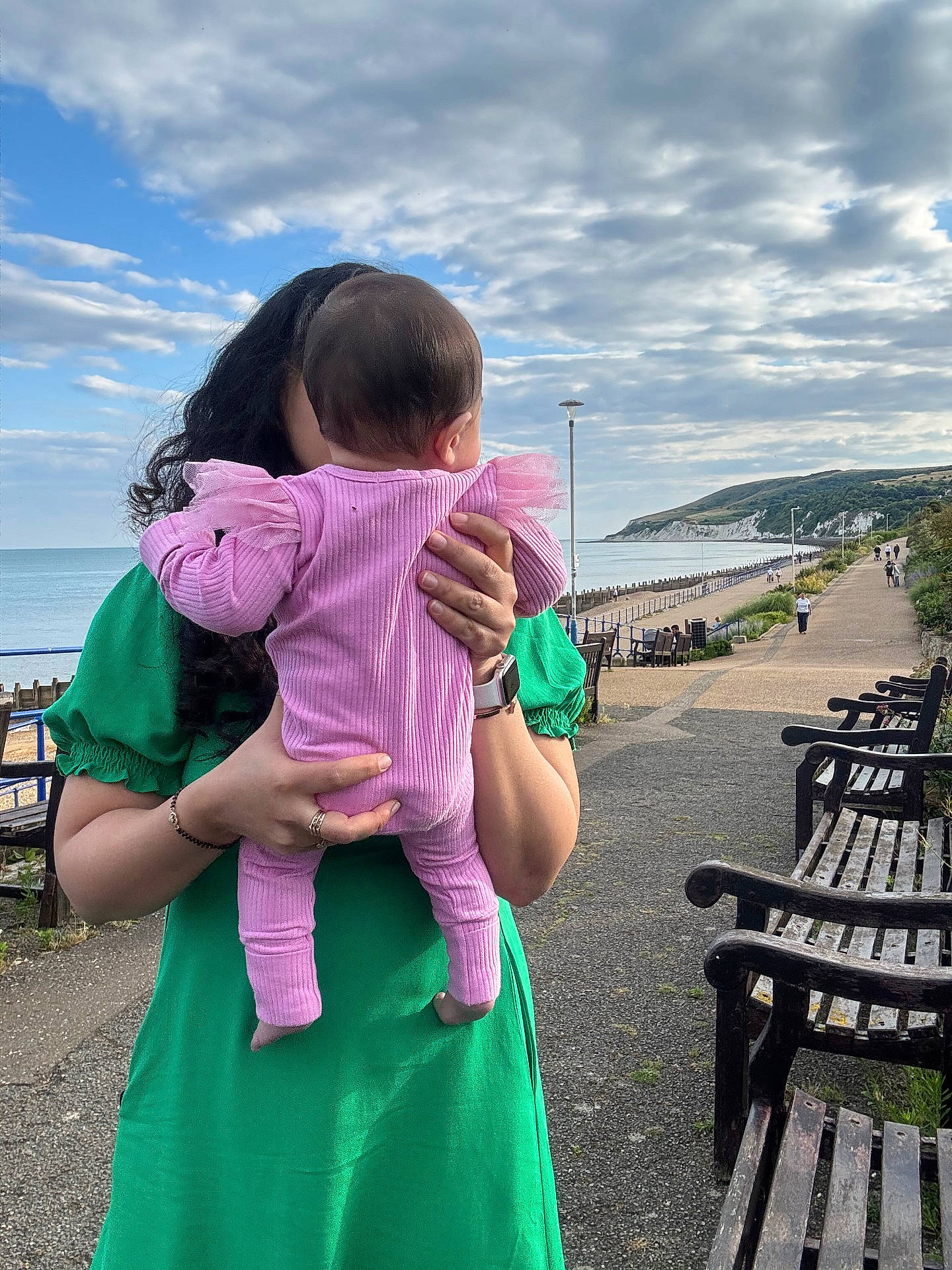 Srinaya joined the competition — help win amazing prizes! baby, beach, benches, casual, cliff, cloudy_sky, coast, daytime, green_dress, hand, holding, nature, outdoor, pathway, people, pink_outfit, scenic, sea, walking, woman
