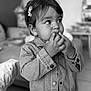Alba participe au concours pour gagner de l'argent avec cette photo : toddler, child, denim_jacket, hair_clip, indoor, portrait, curious, cute, baby, person, face, hand, long_sleeves, young_child, casual_clothing, looking_away, black_and_white, floor_tiles, furniture, candid