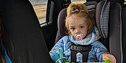 Maria joined the competition — help win amazing prizes! bottle, car_interior, car_seat, child, cup, cup_holder, hair, jacket, looking_at_camera, milk, mountains, pacifier, road, seat, seat_belt, tablet, tablet_case, toddler, travel, window