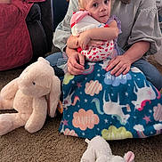 Maria joined the competition — help win amazing prizes! toddler, child, adult, stuffed_toy, blanket, unicorn, plush_toy, carpet, indoor, pigtails, holding, cuddling, cute, seated, colorful, person, soft_toys, family, cozy, home