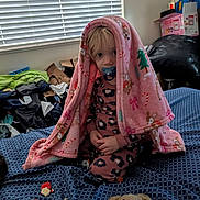 Maria is registered to the contest to win money with this photo: bed, bedspread, blanket, box, child, crumbs, hair, indoor, messy_room, pacifier, pajamas, portrait, sitting, snack, stuffed_animal, teddy_bear, toddler, toy, trophy, window_blinds