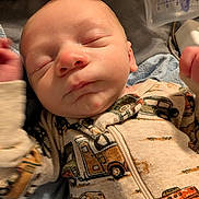 Zachary is registered to the contest to win money with this photo: baby, newborn, sleeping, onesie, face, closed_eyes, infant, cozy, blanket, bottle, burp_cloth, hand, ear, nose, mouth, zipper, vehicle_pattern, soft_lighting, portrait, bed