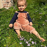 Enoha participe au concours pour gagner de l'argent avec cette photo : toddler, child, grass, flowers, outdoor, sunlight, overalls, corduroy, barefoot, smile, greenery, nature, young_child, sitting, casual_clothing, playful, portrait, daylight, garden, happy