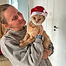 Micky a rejoint le concours — aidez-le/la à gagner de superbes lots ! animal, cat, christmas, door, festive, furniture, gray_sweatshirt, holding, holiday, home, human, indoors, orange_cat, pet, photography, portrait, santa_hat, smiling, woman, wristwatch