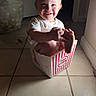 Vylette is registered to the contest to win money with this photo: toddler, child, popcorn_box, smiling, happy, indoor, tile_floor, cute, baby, sitting, holding_foot, playful, small_hands, light_and_shadow, home, person, young_child, funny_pose, foot, bright_eyes