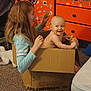 baby, cardboard_box, carpet, casual, child, clothing, dresser, face, fun, furniture, hair, happy, home, indoor, person, playful, room, smiling, stickers, toy