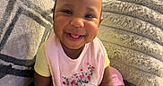 Emmani joined the competition — help win amazing prizes! baby, blanket, child, cozy, cushion, cute, expression, foot, hair_tie, hand, happy, home, indoors, infant, pink_bib, portrait, sitting, skin, smiling, yellow_shirt