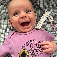 Brynlee joined the competition — help win amazing prizes! baby, smiling, purple_shirt, sunflower, glitter, blanket, checkered_pattern, happy, infant, cute, hand, face, portrait, clothing, toddler, lying_down, expression, child, indoors, closeup