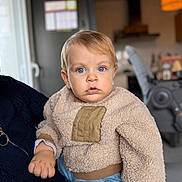 Robin participe au concours pour gagner de l'argent avec cette photo : baby, beige, blue_eyes, blurred_background, casual, child, curious, cute, denim, face, fuzzy_clothing, hand, holding, home, indoor, jeans, person, portrait, sweater, toddler