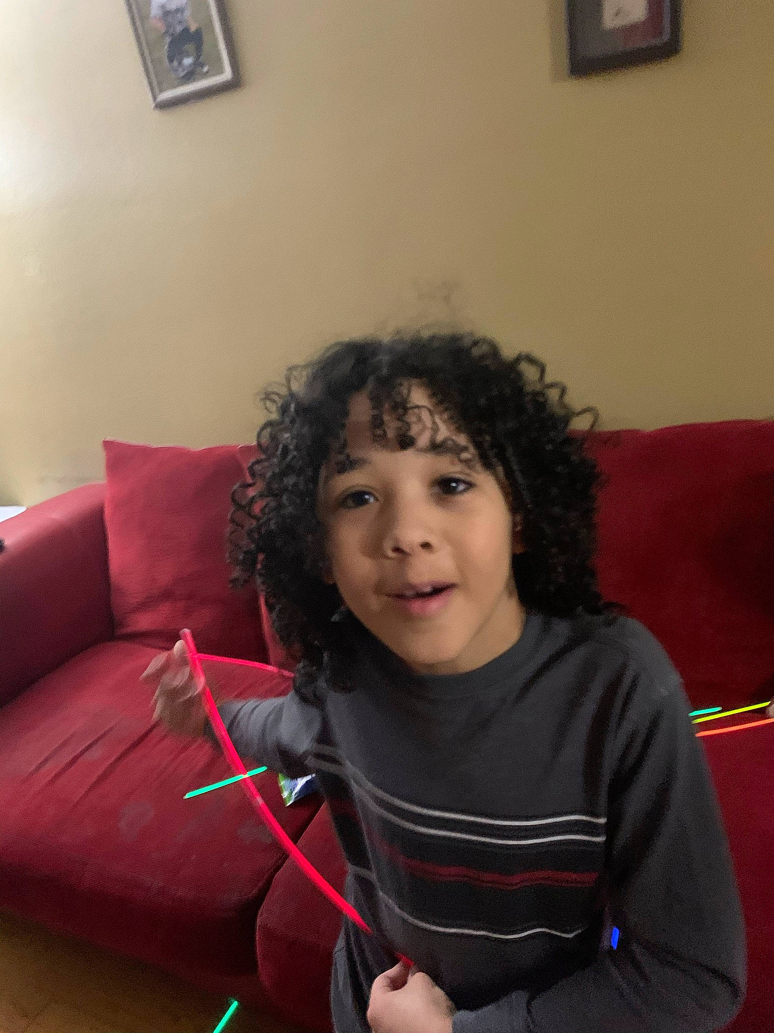 Apollo is registered to the contest to win money with this photo: child, comfort, couch, electronic_device, event, face, facial_expression, flooring, fun, furniture, hair, happy, living_room, person, picture_frame, room, sitting, smile, studio_couch, t_shirt