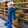 Oaklynn is registered to the contest to win money with this photo: toddler, child, girl, blue_clothing, headband, white_bow, bridge, rusty_railings, wooden_floor, outdoor, autumn, fall_foliage, nature, curious, standing, portrait, fashion, cute, person, daylight
