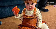 Oaklynn joined the competition — help win amazing prizes! toddler, child, toy, orange, carpet, indoor, couch, adult, seated, clothing, headband, long_sleeve, white_tights, floor, person, home, living_room, furniture, casual, curious