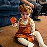 toddler, child, toy, orange, carpet, indoor, couch, adult, seated, clothing, headband, long_sleeve, white_tights, floor, person, home, living_room, furniture, casual, curious