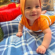 Thomas joined the competition — help win amazing prizes! baby, child, orange_clothing, hood, blanket, plaid, outdoor, grass, drool, hand, smile, face, toy, inflatable, tote_bag, curious, crawling, playful, sunlight, happy
