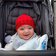 Orhan joined the competition — help win amazing prizes! baby, stroller, red_hat, blanket, smile, child, infant, cozy, outdoor, clothing, baby_accessory, cute, happy, person, portrait, fabric, warm, seat, baby_trend, headwear