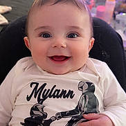 Mylann a rejoint le concours — aidez-le/la à gagner de superbes lots ! baby, child, clothing, cute, expression, eyes, face, hand, happy, indoor, infant, joy, mouth, person, portrait, seated, shirt, sitting, smiling, toddler