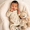 baby, infant, teddy_bear, blanket, soft_texture, cute, cozy, pajamas, socks, smiling, child, plush_toy, comfort, portrait, resting, indoors, warm_colors, sleepwear, adorable, young