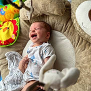 Jacob joined the competition — help win amazing prizes! baby, infant, smiling, laughing, cushion, bear_shape, toy, colorful, blanket, white_clothing, soft_texture, indoor, floor, play_area, child, happy, cute, newborn, person, toddler