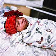 Aaliyah is registered to the contest to win money with this photo: newborn, baby, sleeping, red_headwrap, blanket, footprint_pattern, bed, cozy, indoor, infant, wrapped, peaceful, portrait, child, cute, resting, soft, closeup, headwear, sleep