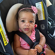 Iris is registered to the contest to win money with this photo: baby, car_seat, child, infant, pink_headband, pink_clothing, seatbelt, safety, car_interior, closeup, drool, cute, hands, face, eyes, expression, young_child, portrait, warning_label, seat