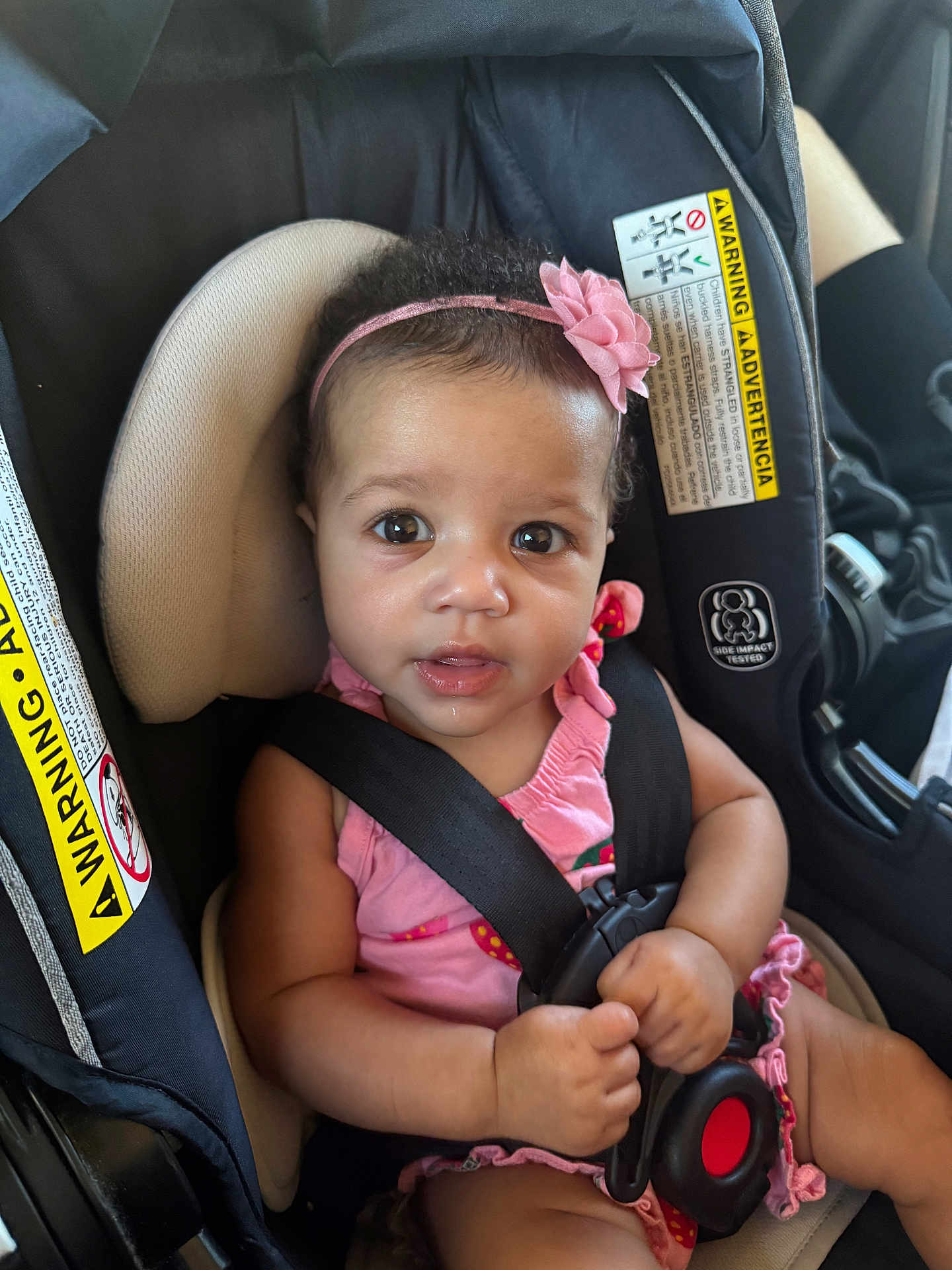 Iris is registered to the contest to win money with this photo: baby, car_seat, child, infant, pink_headband, pink_clothing, seatbelt, safety, car_interior, closeup, drool, cute, hands, face, eyes, expression, young_child, portrait, warning_label, seat