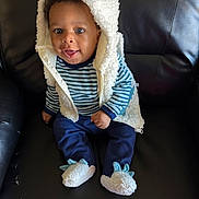 Maziyon is registered to the contest to win money with this photo: baby, child, smile, blue_clothing, striped_shirt, fluffy_vest, hood, slippers, dinosaur_slippers, black_chair, leather_chair, sitting, happy, cute, indoors, portrait, young_child, person, cozy, warm_clothing