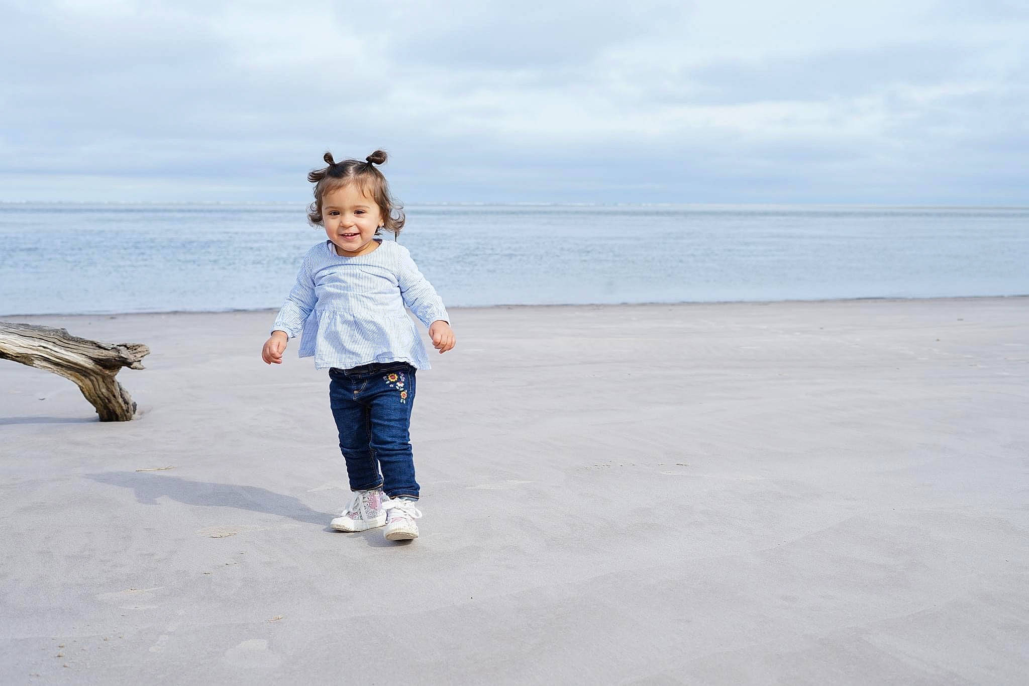 Nalani is registered to the contest to win money with this photo: baby_toddler_clothing, beach, cloud, denim, fun, gesture, happy, horizon, jeans, joy, landscape, leisure, people_in_nature, people_on_beach, person, sky, sleeve, smile, toddler, travel