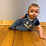 baby, blue_clothing, bunny_design, casual, child, crawling, curious_expression, cute, flooring, home, indoor, infant, one_child, overalls, person, playful, power_socket, wall, wide_eyes, wooden_floor