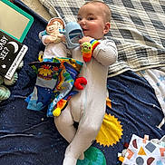 Anthony joined the competition — help win amazing prizes! baby, infant, onesie, plush_toy, teething_toy, blanket, space_theme, book, floor, child, smiling, toy, colorful, soft_toy, footwear, person, indoor, cute, happy, laying_down