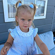 Christiana joined the competition — help win amazing prizes! child, girl, blonde_hair, pigtails, blue_hair_ties, striped_dress, frilly_collar, outdoor, window, gray_siding, cushion, bench, curious, smile, portrait, person, skin, face, earrings, sunlight
