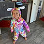 Christiana joined the competition — help win amazing prizes! toddler, child, onesie, costume, bunny_ears, smile, barefoot, indoor, kitchen, floor, rug, colorful_clothing, happy, person, portrait, headwear, young_child, playful, home, wooden_floor