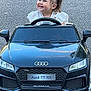 Tyana a rejoint le concours — aidez-le/la à gagner de superbes lots ! asphalt, audi, black, car_toy, child, clothing, cute, daylight, driving, happy, head, outdoor, person, pigtails, play, small_car, smiling, toddler, toy_car, vehicle