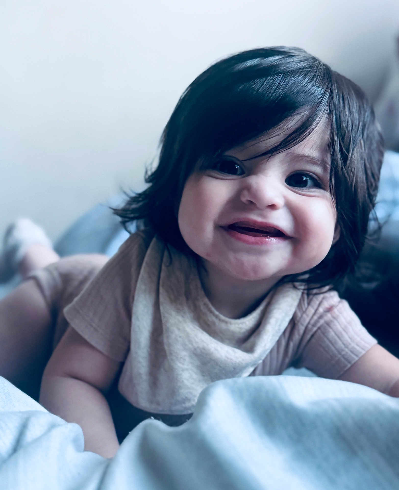 Ariella is registered to the contest to win money with this photo: baby, bed, blanket, child, clothing, cozy, cute, eyes, face, hair, happy, indoors, infant, lying_down, person, portrait, skin, smile, toddler, young