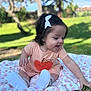 baby, blanket, bow, child, cute, daylight, footwear, girl, grass, greenery, happy, heart_pattern, nature, outdoor, pink, playful, portrait, short_sleeve, sitting, smiling