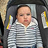baby, child, stroller, striped_shirt, jeans, serious_expression, face, person, clothing, hands, seat, warning_label, outdoor, casual, portrait, cute, infant, young_child, sitting, closeup