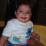 Ismael is registered to the contest to win money with this photo: baby, child, smiling, sitting, tshirt, shorts, floor, indoor, cute, face, cheeks, person, childhood, happy, skin, legs, hand, eyes, hair, casual_clothing