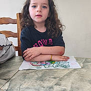 Shannon a rejoint le concours — aidez-le/la à gagner de superbes lots ! artwork, black_tshirt, blue_eyes, bracelet, chair, child, curly_hair, drawing, expression, home, indoor, long_hair, marble_table, mirror, person, portrait, sitting, table, wooden_chair, young_child