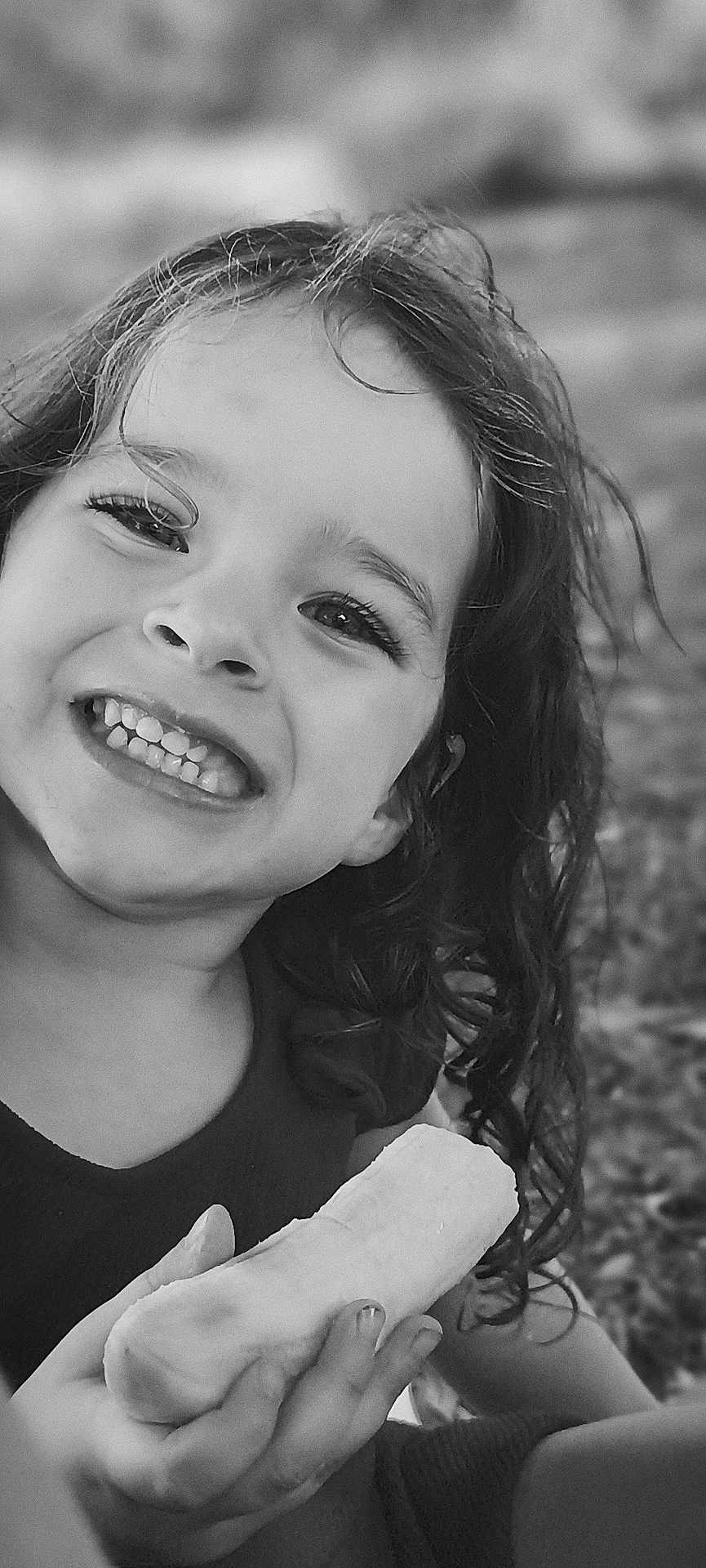 Shannon participe au concours pour gagner de l'argent avec cette photo : banana, black_and_white, casual, child, close_up, curly_hair, cute, expression, face, fruit, hand, happy, natural_light, outdoor, person, portrait, skin, smiling, teeth, young