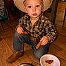 child, cowboy_hat, plaid_shirt, jeans, boots, floor, wooden_floor, food, chicken_tenders, paper_plate, colander, indoor, kneeling, person, young_child, snack_time, casual, brown, cute, portrait