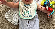 Luca is registered to the contest to win money with this photo: baby, infant, carpet, bib, toy, blanket, socks, footwear, person, child, cute, clothing, striped, blue, white, indoor, floor, smiling, lying_down, home