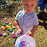 toddler, child, bucket, plastic_eggs, easter_eggs, outdoor, grass, sunlight, clothing, shirt, toy, play, person, head, face, hand, colorful, nature, daylight, event
