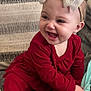 Karter is registered to the contest to win money with this photo: baby, child, smiling, red_clothing, headband, bow, couch, cushion, indoor, happy, person, foot, sitting, portrait, infant, cute, fabric, pattern, home, cozy