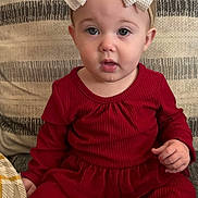 Karter is registered to the contest to win money with this photo: baby, child, red_outfit, headband, bow, couch, cushion, indoor, portrait, cute, infant, sitting, face, expression, cozy, fabric, soft, texture, clothing, person