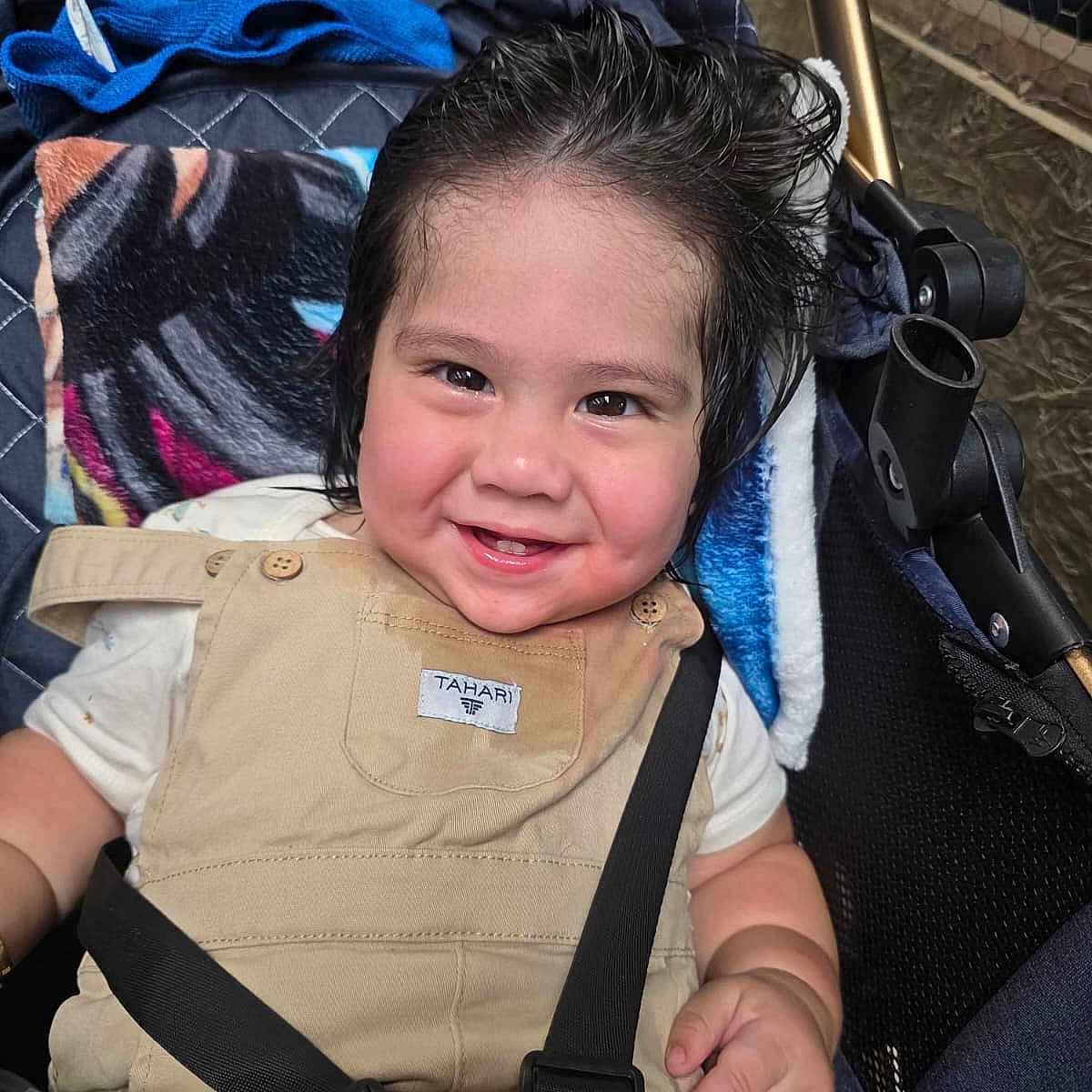 Ryan Mavo is registered to the contest to win money with this photo: baby, child, smiling, happy, portrait, stroller, seated, infant, overalls, clothing, harness, safety_strap, blanket, chair, face, eyes, hair, indoor, close_up, photography