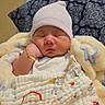 newborn, baby, sleeping, infant, portrait, blanket, swaddle, hat, indoors, bed, pillow, cozy, peaceful, face, closed_eyes, child, textile, knitted_blanket, bracelet, home
