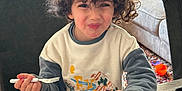 Paul a rejoint le concours — aidez-le/la à gagner de superbes lots ! child, couch, curly_hair, cushion, dining, food, fork, fruit, happy, indoor, living_room, meal, natural_light, orange_fruit, person, plate, smile, strawberries, sweatshirt, table