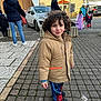 adult, building, car, casual, child, child_in_costume, cobblestone, costume, curious_expression, curly_hair, daylight, group, jacket, outdoor, people, sidewalk, spiderman_pants, street, urban, winter_clothing