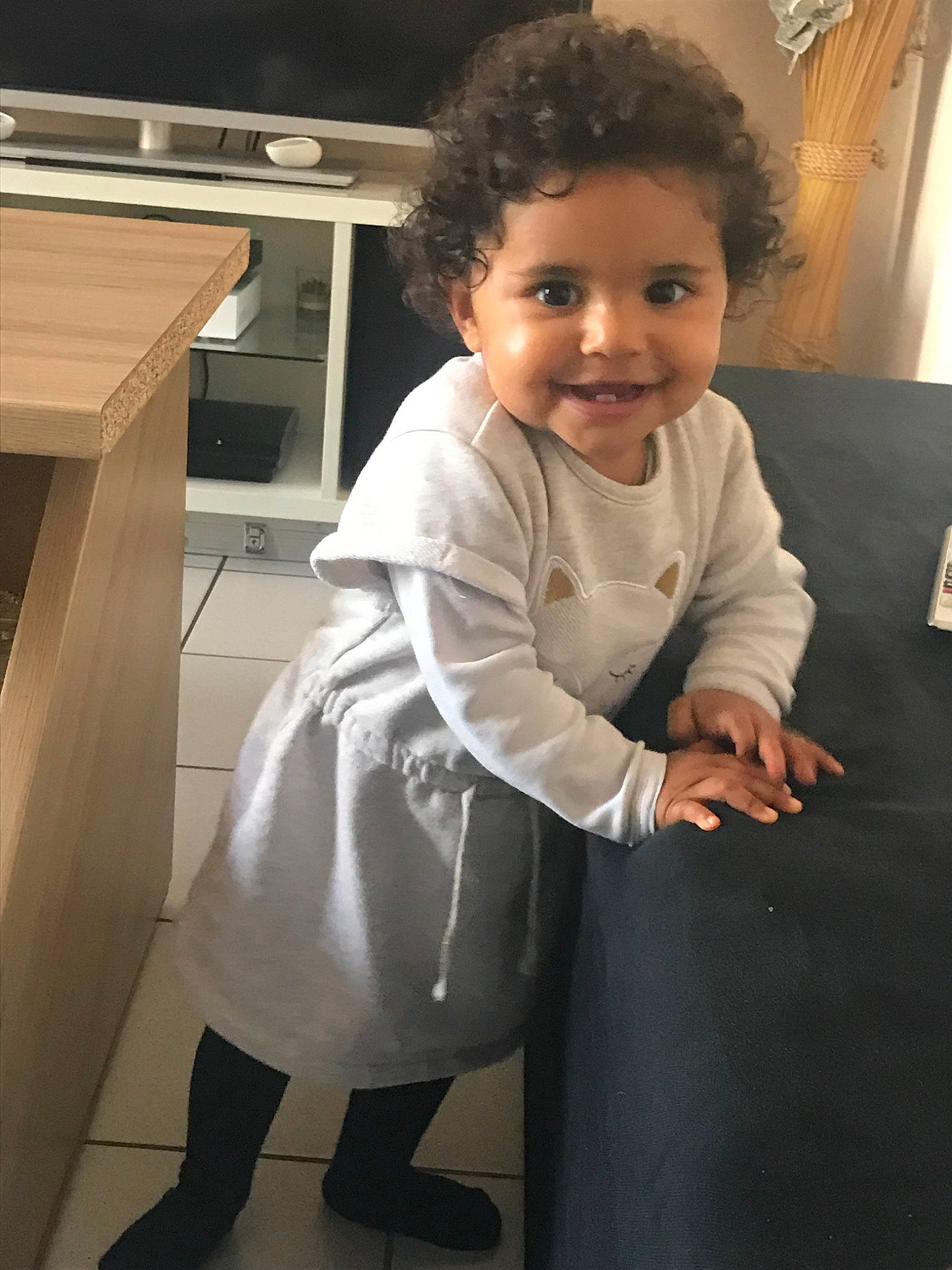 Liya participe au concours pour gagner de l'argent avec cette photo : baby, cheek, child, face, joy, leg, outerwear, person, room, smile, standing, toddler